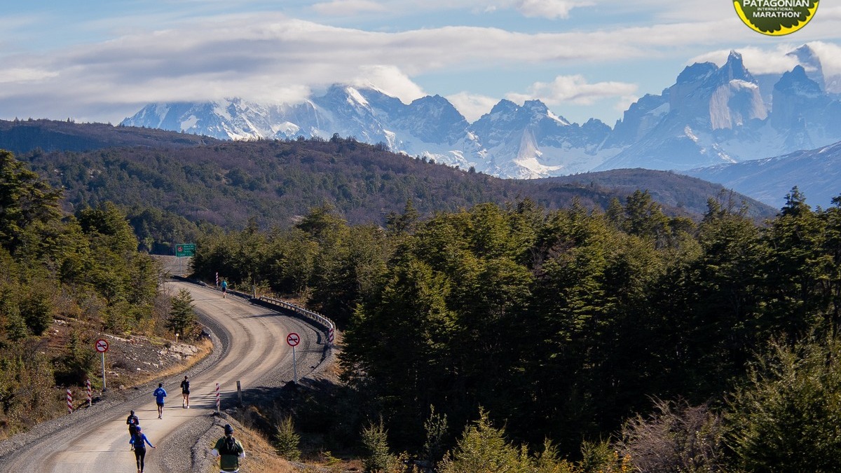 Corredores avanzando por un camino de tierra hacia los macizos nevados de Torres del Paine